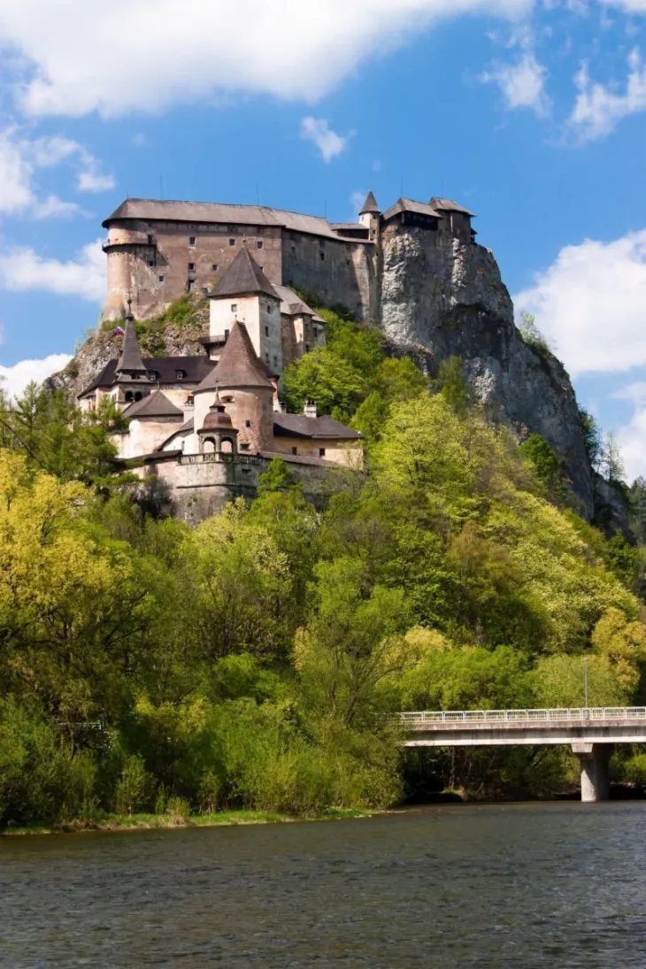 Die Burg Orava in Slowenien liegt auf einer zerrissenen Bergkuppe inmitten eines grünen Waldes.